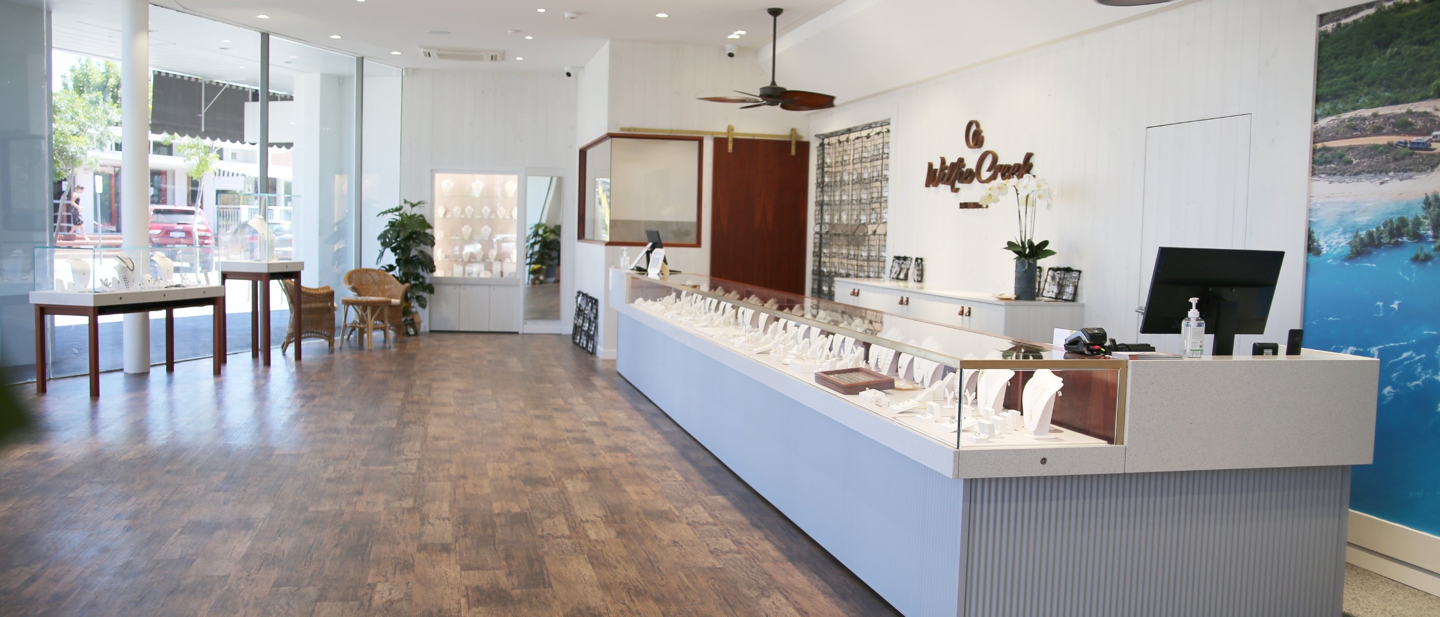 The interior of the Willie Creek Pearls jewellery showroom in Cottesloe, featuring hardwood floors, a wicker table and chair set, and display cabinets showcasing Australian South Sea pearl jewellery.