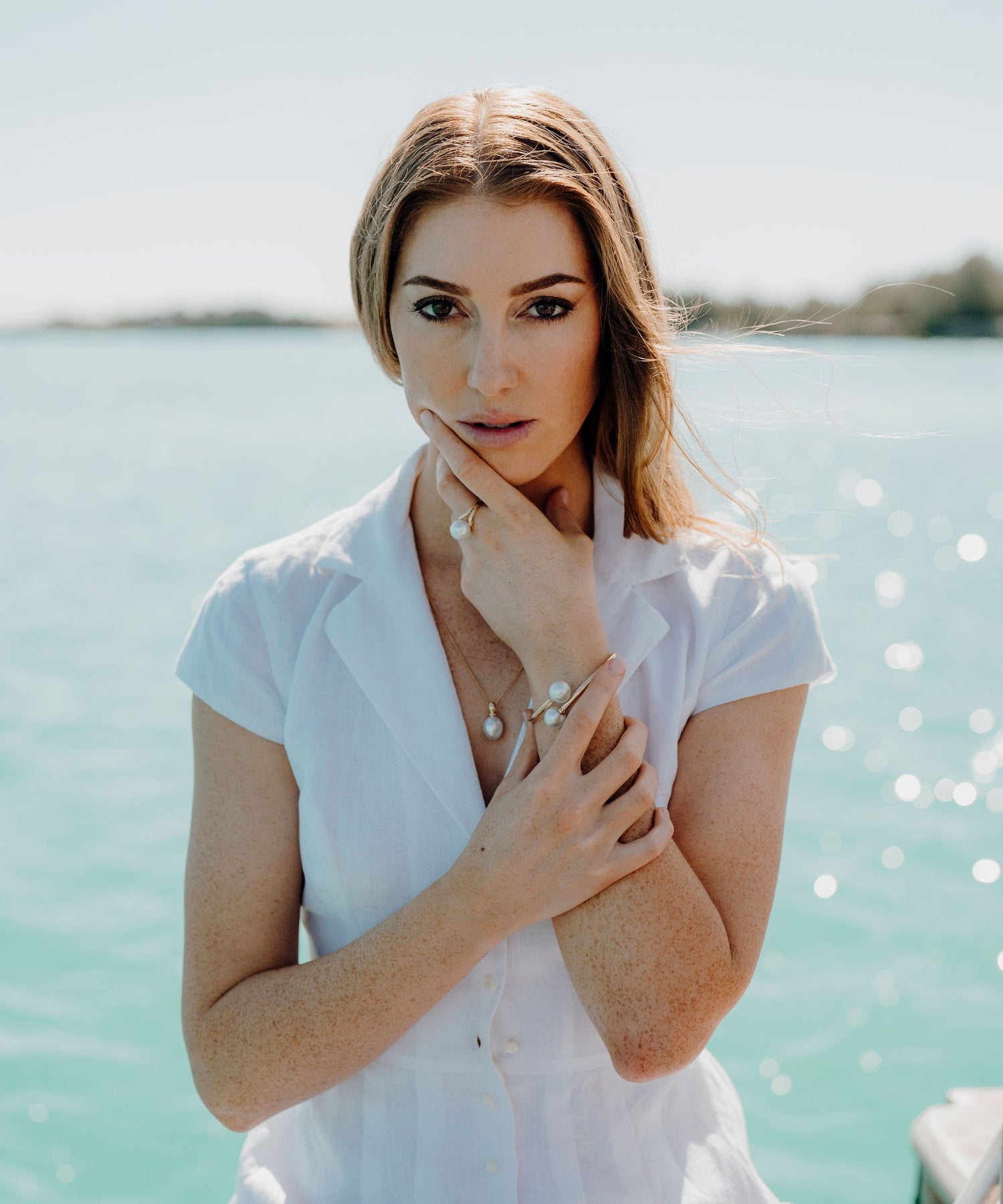 A model stands in front of Willie Creek in Broome, wearing the Willie Creek Pearls Everyday Classic Pearl Jewellery Collection, including a pearl pendant, bangle, and ring.